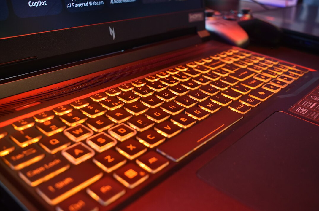 Hands writing notes next to a laptop on a desk